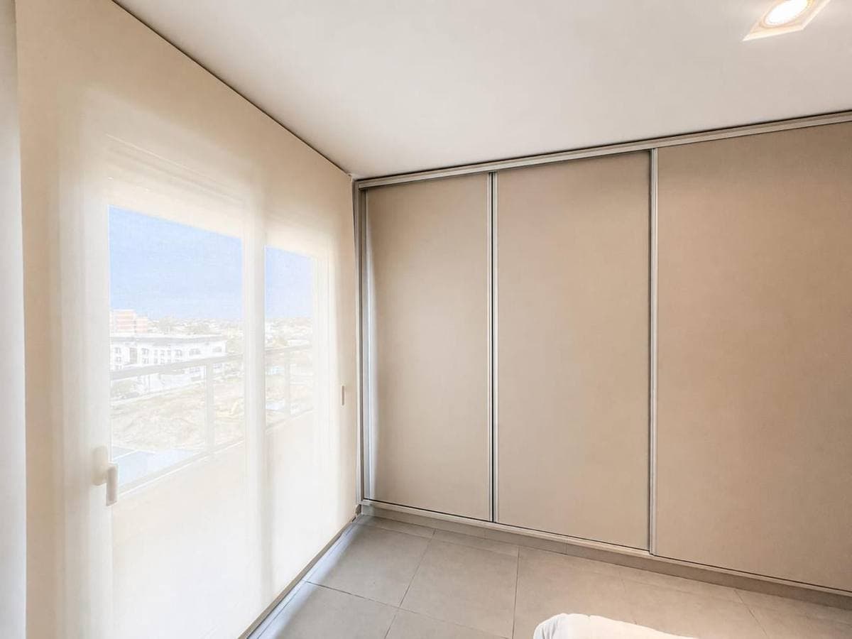 Ventanal con estor blanco translúcido junto a un armario empotrado de tres puertas correderas beige.