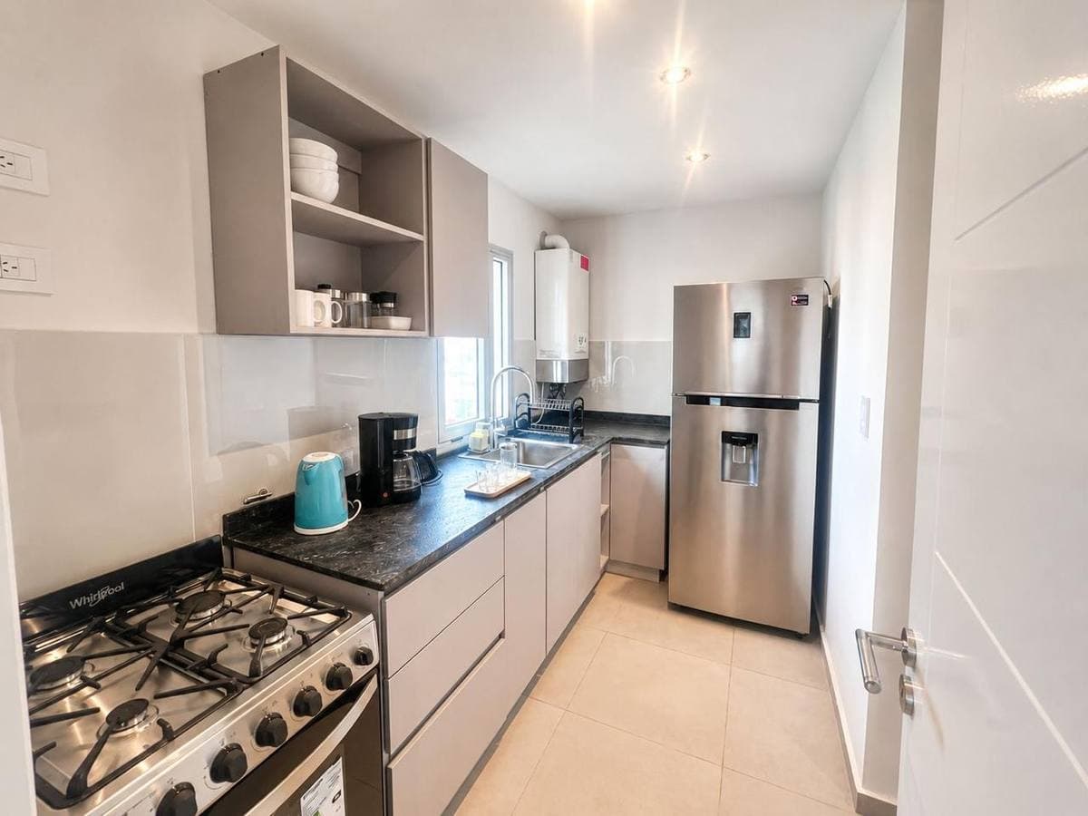 Cocina moderna con electrodomésticos de acero inoxidable, encimeras de granito y gabinetes gris claro.
